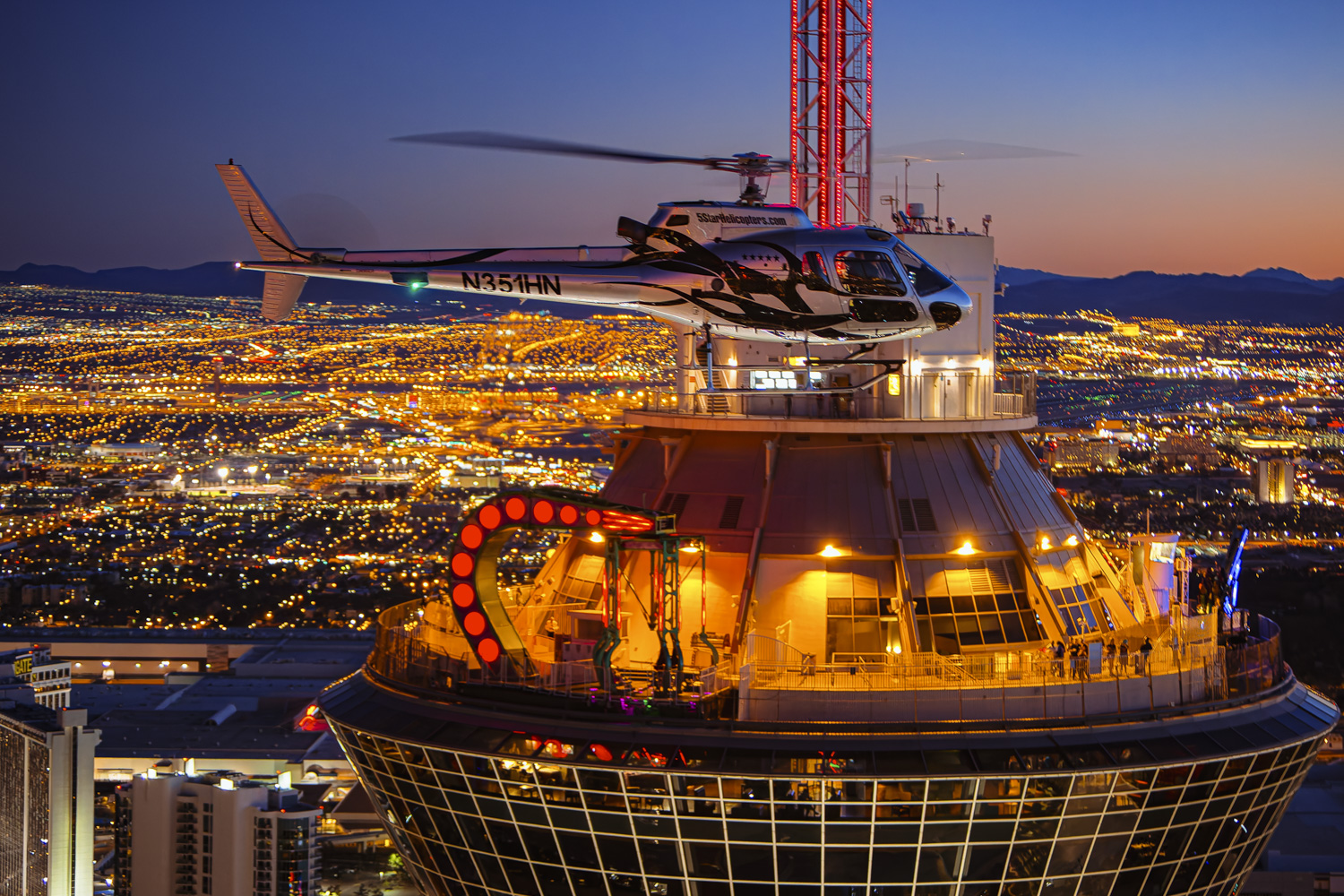 A helicopter flies over the Stratosphere Tower at sunset, offering breathtaking views of the Las Vegas Strip and Nevada skyline during Las Vegas helicopter tours.